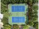 Aerial view of two blue and green tennis courts surrounded by lush green trees in a residential community at 512 Hallburg Ct, Wake Forest, NC 27587