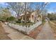 Charming yellow two-story home with mature trees, lush landscaping and a white picket fence at 529 Hillcrest Ave, Burlington, NC 27215