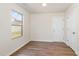 Empty bedroom with wood-look flooring, a window, and a white paneled door at 627 Hastings Rd, Mebane, NC 27302