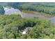 Aerial view of a home nestled amongst lush trees on a property with lake frontage at 6452 Therfield Dr, Raleigh, NC 27614