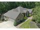 Aerial view of a brick home featuring an attached garage, manicured lawn, and a paved driveway at 6452 Therfield Dr, Raleigh, NC 27614