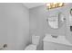 Simple half bath featuring a white vanity, round mirror and neutral color scheme at 7706 Falcon Rest Cir, Raleigh, NC 27615