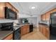 Well-lit kitchen featuring wood cabinets and black appliances overlooking the dining area at 7706 Falcon Rest Cir, Raleigh, NC 27615
