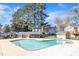 Community swimming pool with lounge seating, lush trees, and a neighborhood building at 7727 Ohmann Ct, Raleigh, NC 27615