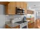 Close-up of a kitchen featuring a stove, microwave, granite countertops, and wood cabinets at 901 Emory Ln, Raleigh, NC 27609