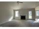 Spacious living room featuring a fireplace, neutral carpet, and ample natural light from two windows at 102 Heatherglenn Cir, Princeton, NC 27569