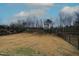 Large fenced backyard with a mix of dry grass and new spring growth with mature trees in the background at 110 Manor Stone Dr, Clayton, NC 27527