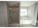 Bathroom featuring tiled walk-in shower with bench and soaking tub, with a nearby window for great light at 110 Manor Stone Dr, Clayton, NC 27527