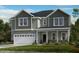 Charming two-story home with a white garage door and lush green landscaping, creating an inviting curb appeal at 1129 Sun Springs Rd, Wake Forest, NC 27587