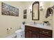 Powder room featuring a dark wood vanity, framed mirror, sconces, and neutral walls at 113 Valley Ln, Pittsboro, NC 27312