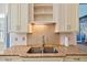 Close-up of kitchen sink with granite countertops, backsplash, and custom cabinets at 119 Cardinal Crest Ct, Pittsboro, NC 27312