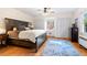 Bedroom with hardwood floors, carved headboard, bright window seat, and custom area rug at 122 W Woodridge Dr, Durham, NC 27707