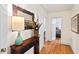 Hallway with hardwood floors, decorative table with mirror, and open doorway to bedroom at 122 W Woodridge Dr, Durham, NC 27707