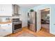 Modern kitchen with stainless steel appliances, white cabinets, and hardwood floors at 122 W Woodridge Dr, Durham, NC 27707