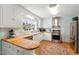 Bright kitchen featuring white cabinets, butcher block countertops, stainless steel appliances, and colorful rug at 122 W Woodridge Dr, Durham, NC 27707