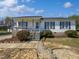 Charming single-story home with white siding, blue shutters, a covered porch, and landscaped front yard at 125 Wynnridge Dr, Angier, NC 27501