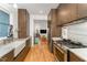 Modern kitchen with stainless steel appliances, marble countertops, wood cabinets, and hardwood floors overlooking living area at 132 Fiori Hill S Dr, Hillsborough, NC 27278