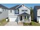Charming two-story home with a covered front porch, attached garage, and blue and gray color scheme at 1417 Underbrush Dr, Durham, NC 27703