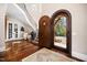 Bright foyer with a curved staircase, arched doorway, hardwood floors, and large decorative vases at 2207 Oxford Rd, Raleigh, NC 27608