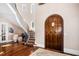 Grand foyer with curved staircase, hardwood floors, a decorative rug, and striking arched door at 2207 Oxford Rd, Raleigh, NC 27608