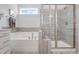 Elegant bathroom featuring a soaking tub and glass-enclosed shower with stylish gray tiling at 228 Nahunta Dr, Apex, NC 27539