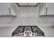 Close-up of a modern kitchen stove with white subway tile backsplash and quartz countertops at 228 Nahunta Dr, Apex, NC 27539