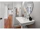 Elegant bathroom featuring a pedestal sink, oval mirror, stylish fixtures, and hardwood flooring at 2704 St Marys St, Raleigh, NC 27609