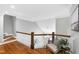 Hallway with wood floors, decorative chair and staircase with white railings at 2704 St Marys St, Raleigh, NC 27609