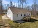 Aerial view of the back of a white home with a brown roof, showing a deck, and concrete patio at 302 Weaver Ridge Rd, Rougemont, NC 27572