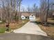 View of a charming one-story home with a two-car garage and long driveway surrounded by trees at 302 Weaver Ridge Rd, Rougemont, NC 27572