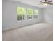 Bright bedroom features carpet, ceiling fan, and three windows with views of lush greenery at 303 Old Fashioned Way, Lillington, NC 27546