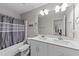 Bright bathroom featuring double sink vanity with a shower-tub combo and gray shower curtain at 35 Wolf Ridge Ct, Willow Springs, NC 27592