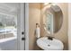 Half bathroom with a pedestal sink, round mirror, and access to an outdoor space at 3504 Griffice Mill Rd, Raleigh, NC 27610