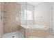 Relaxing bathroom includes a shower and soaking tub near a window that provides natural light at 4005 Freesia Ct, Zebulon, NC 27597