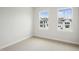 Empty bedroom with neutral carpet and trim featuring two windows with neighborhood views at 4720 Cypress Tree Ln, Raleigh, NC 27612