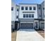 Modern townhome boasts a gray garage door, a concrete driveway and neutral paint colors at 4720 Cypress Tree Ln, Raleigh, NC 27612