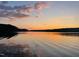 Picturesque lake view featuring sunset colors reflected in the calm waters and trees in the background at 529 Flanagan Rd, Henderson, NC 27537