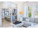 Bright living room showcasing stylish gray sofa, oversized windows, and open concept with kitchen at 664 Sun Meadow Dr, Wake Forest, NC 27587