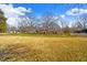 Spacious yard with grass leading to a brick home and outbuildings under a blue sky at 712 Springwood Ave, Gibsonville, NC 27249