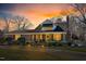 Charming brick home with a cozy front porch, manicured landscaping, and a beautiful sunset at 712 Springwood Ave, Gibsonville, NC 27249