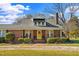 Brick home with well-manicured landscaping, mature trees, and a bright yellow front door at 712 Springwood Ave, Gibsonville, NC 27249