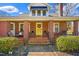 Charming front porch with brick columns, seating, and a bright yellow door at 712 Springwood Ave, Gibsonville, NC 27249