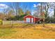 Red outbuilding with a garage door and white fence in a grassy backyard at 712 Springwood Ave, Gibsonville, NC 27249