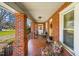 Inviting side porch featuring colorful seating, patterned tile flooring, and brick columns at 712 Springwood Ave, Gibsonville, NC 27249