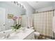 Bathroom featuring dual sinks, decorative mirror, and patterned shower curtain at 7604 Derek Dr, Raleigh, NC 27613