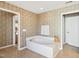 A soaking tub is surrounded by a tile floor and a neutral color patterned wallpaper at 7604 Derek Dr, Raleigh, NC 27613