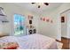 Bright bedroom showcasing a view of the outside, decorative display cabinet, ceiling fan, and rug at 7687 Mattie Rd, Rocky Mount, NC 27803
