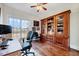 Office area showcasing large built-in wooden shelving and drawers, hardwood floor, and large windows at 7687 Mattie Rd, Rocky Mount, NC 27803