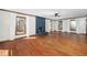 Spacious living room with hardwood floors, a blue brick fireplace, and large windows with white curtains at 7917 Blaney Franks Rd, Apex, NC 27539