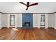 Bright living room featuring a blue brick fireplace, wood trim, a ceiling fan, and three big windows at 7917 Blaney Franks Rd, Apex, NC 27539